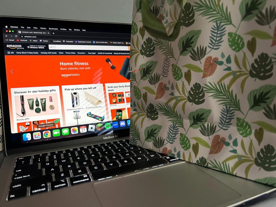 A gift bag sitting on a laptop representing online shopping, with the laptop showing the Amazon website.