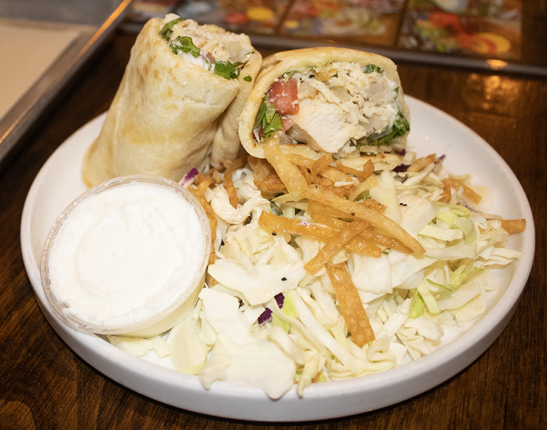 The Chicken Wrap is a garlic lover’s delight that features shredded chicken in Naan bread, with romaine lettuce, tomatoes, and grilled onions. The creamy garlic spread is a Persian recipe and is made fresh, in-house. 